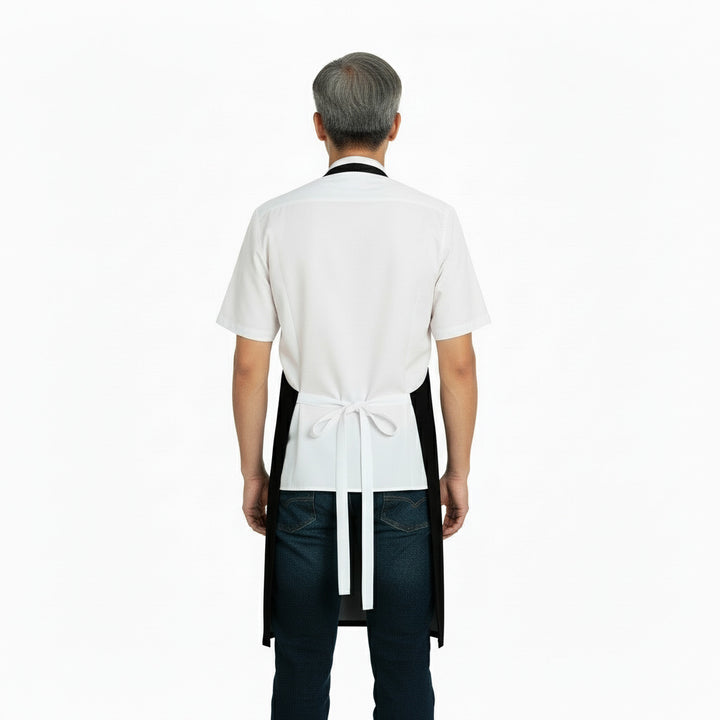 Person wearing a white shirt, black apron, and jeans on a white background