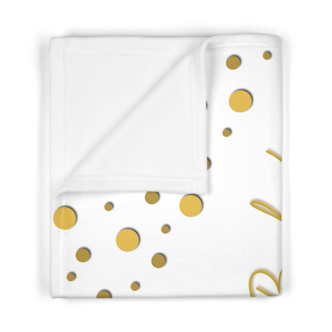 Folded white blanket with gold polka dots on a white background