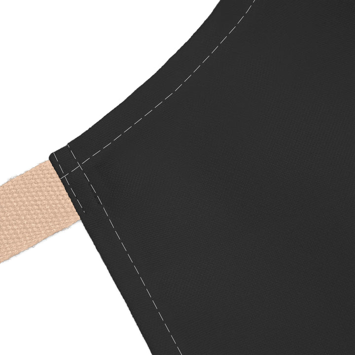 Close-up of a black apron with beige strap on a white background
