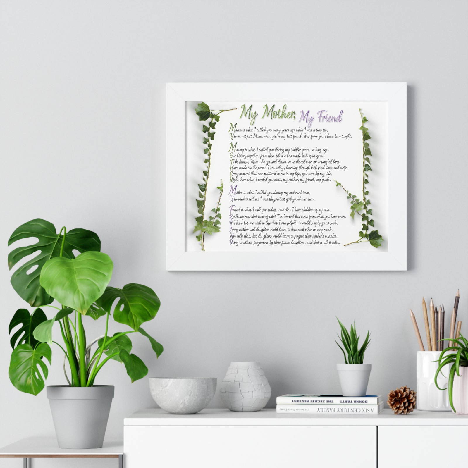Framed poem titled 'My Mother, My Friend' on a wall with decorative plants and items below.