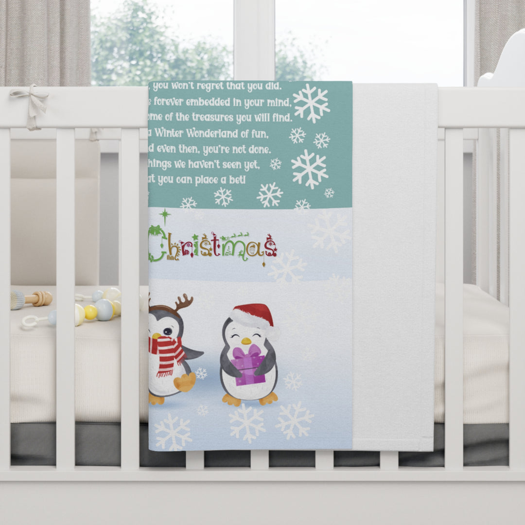 Baby crib with a decorative blanket featuring penguins and Christmas text.