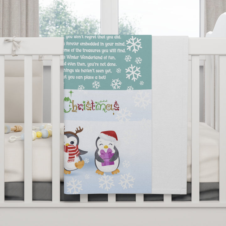 Baby crib with a decorative blanket featuring penguins and Christmas text.