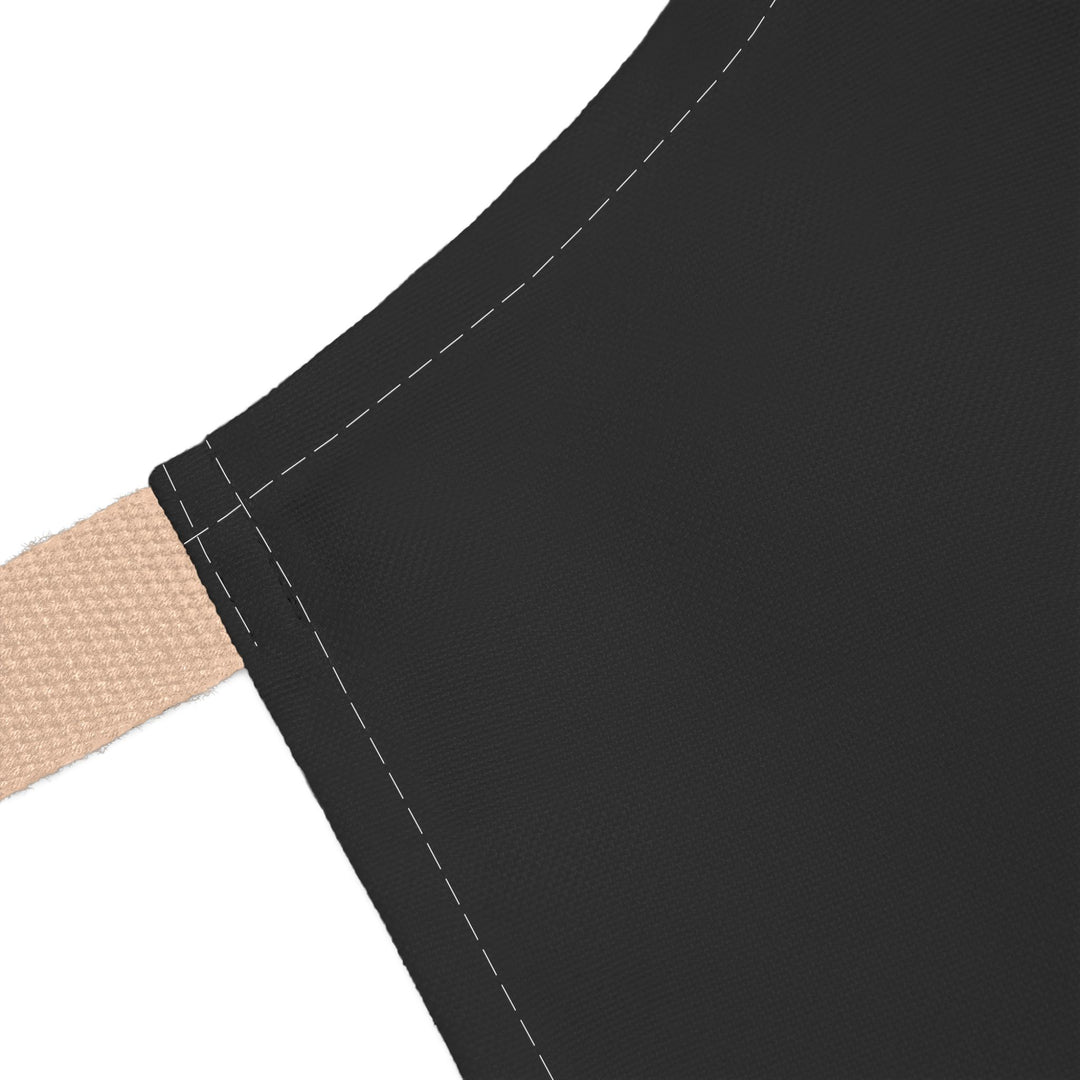 Close-up of a black apron with beige strap on a white background